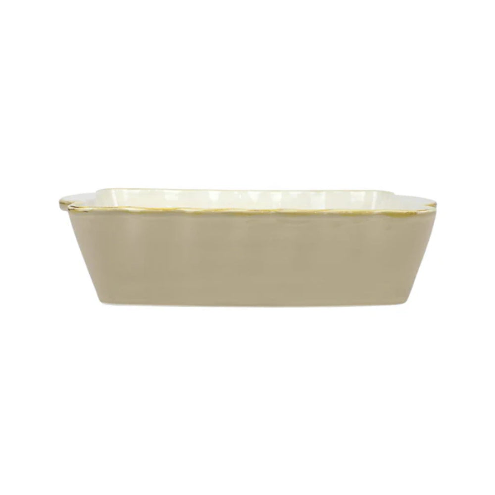 A medium beige rectangular stoneware baker with scalloped edges and gold rim with a white interior