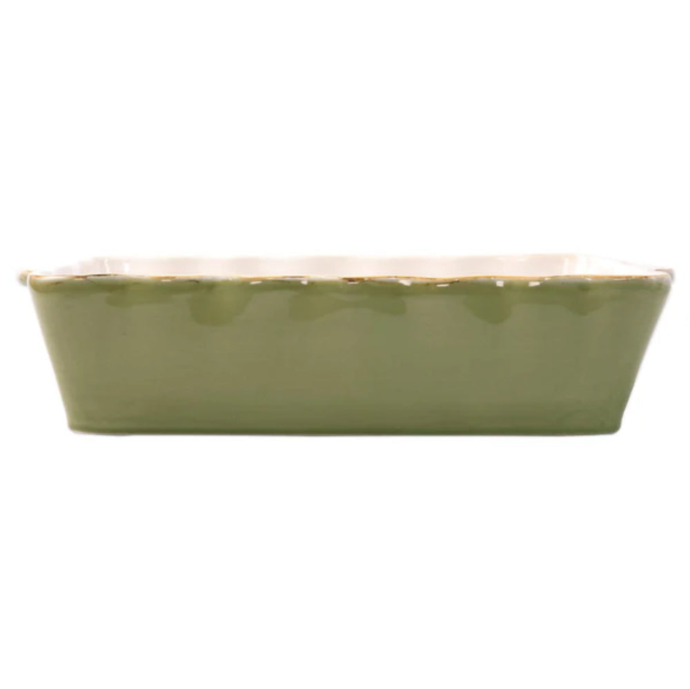 Large green rectangular baking dish with a scalloped edge and gold rim with a white intior on a white background