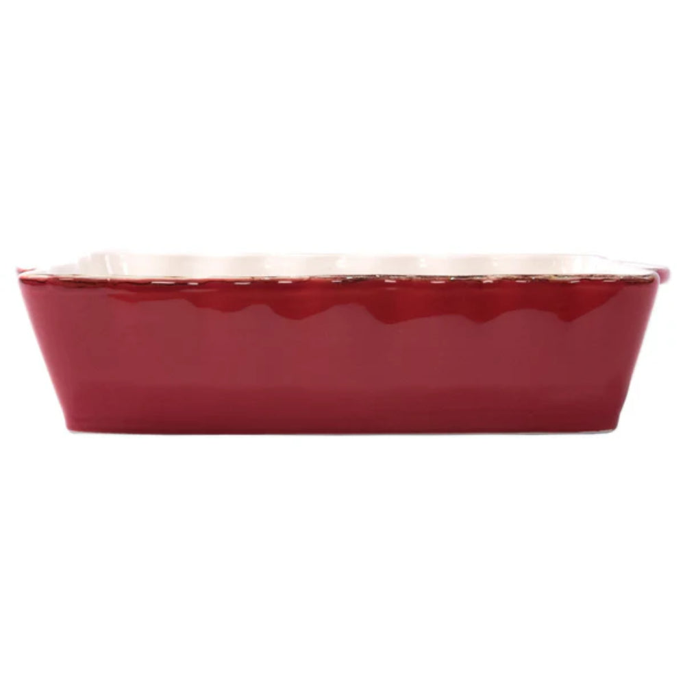 Large red rectangular baking dish with a scalloped edge and gold rim with a white intior  on a white background