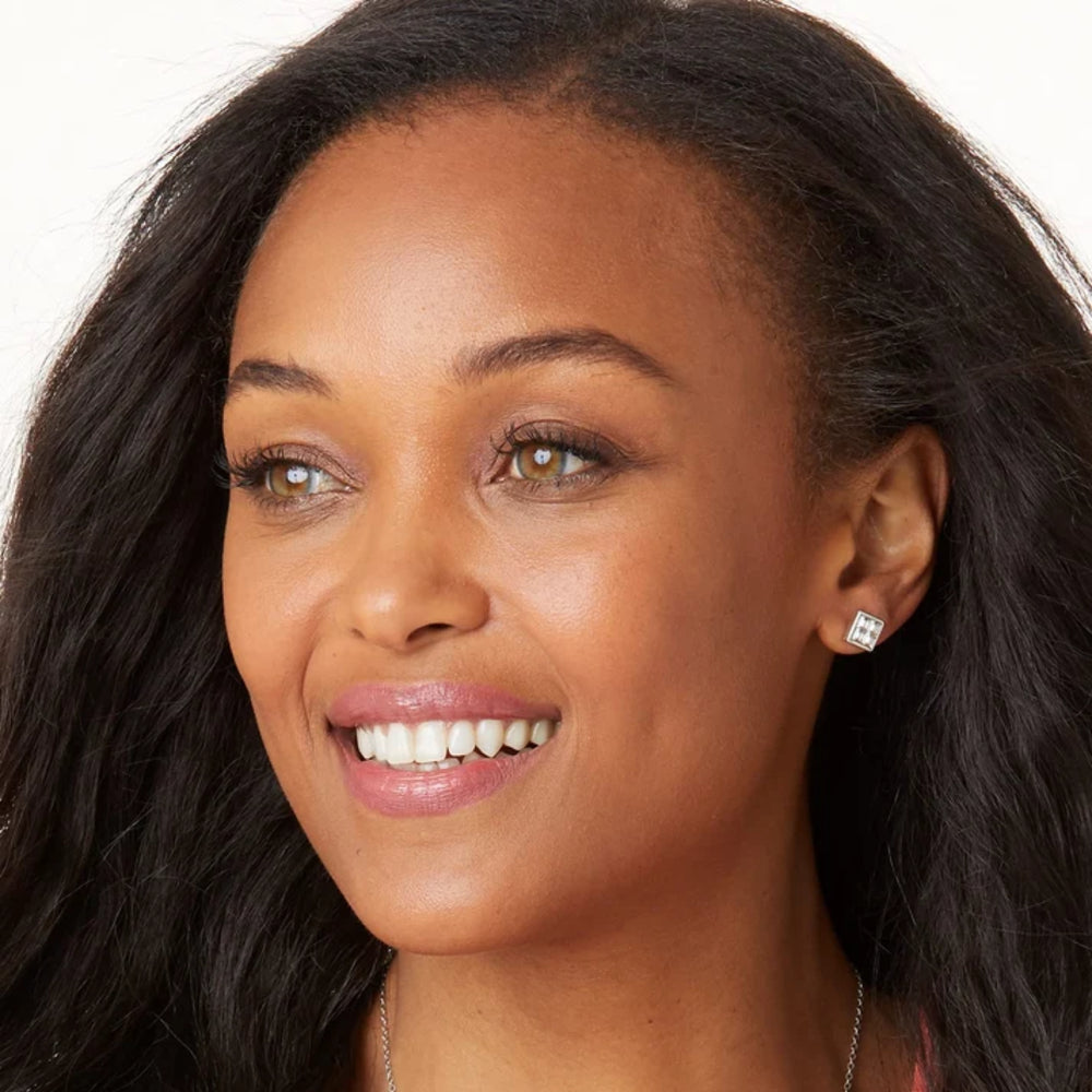 Close-up of a woman with dark hair and earrings on a white background
