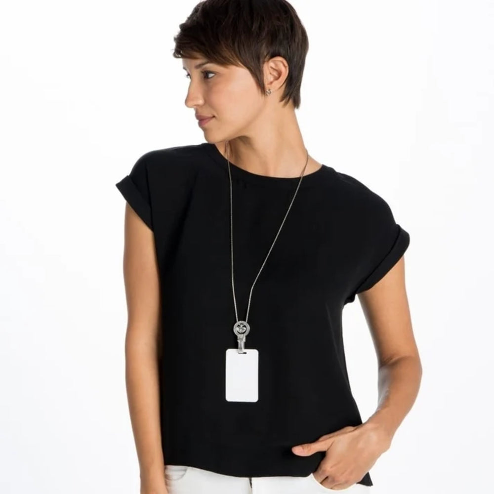 A woman wearing a black short-sleeve top with a silver necklace and a blank white ID badge, shown against a plain white background.
