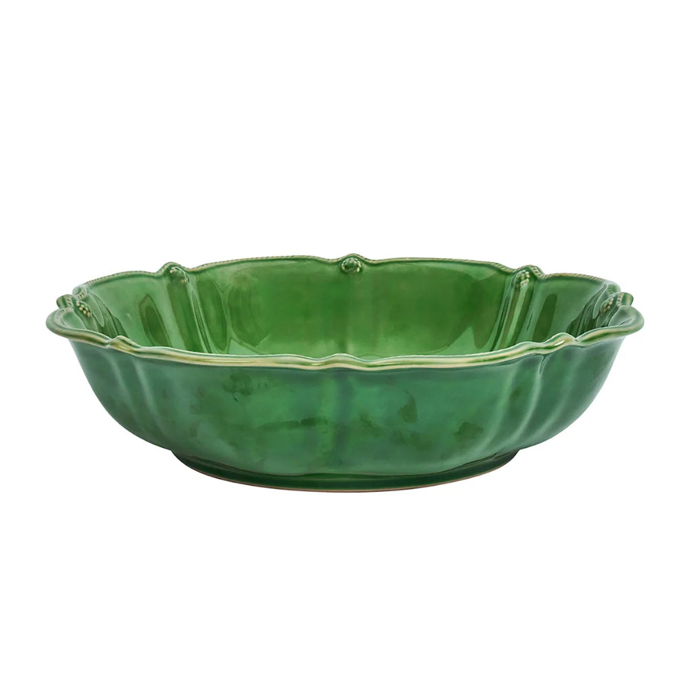 Green ceramic bowl with scalloped edge on a white background