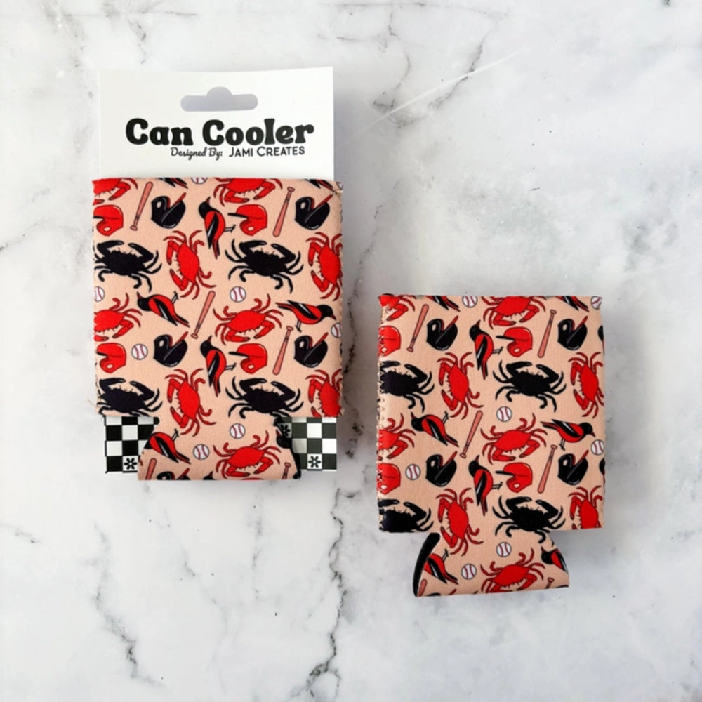 A set of two fabric can coolers with a red and black crab pattern on a beige background, displayed on a white marble surface. One cooler is shown folded with its white cardboard hanger card, and the other is shown flat.