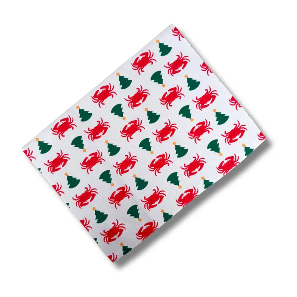A rectangular white fabric item, likely a napkin or small tablecloth, featuring a repeating Christmas pattern of red crabs, green Christmas trees, and small gold ornaments, shown on a white background with a soft drop shadow.