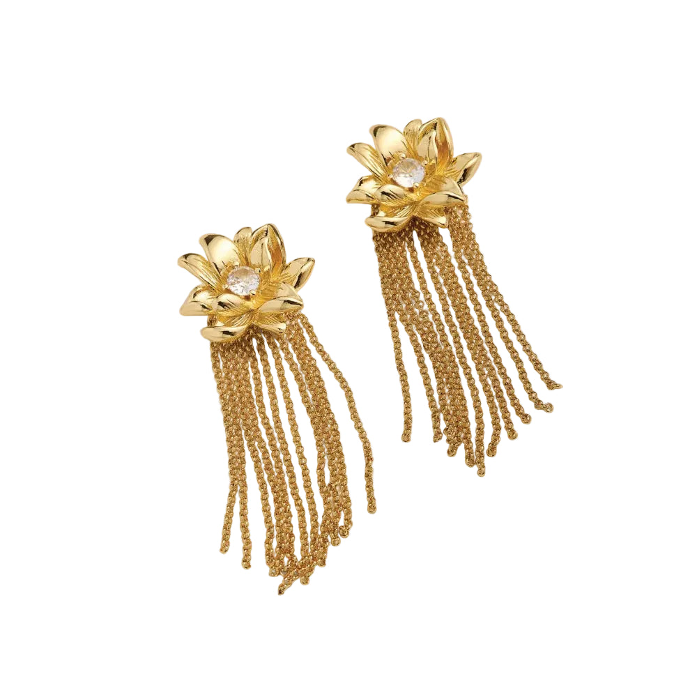 A pair of gold magnolia flower dangle earrings with a clear central gemstone and cascading chain fringe, displayed on a white background.
