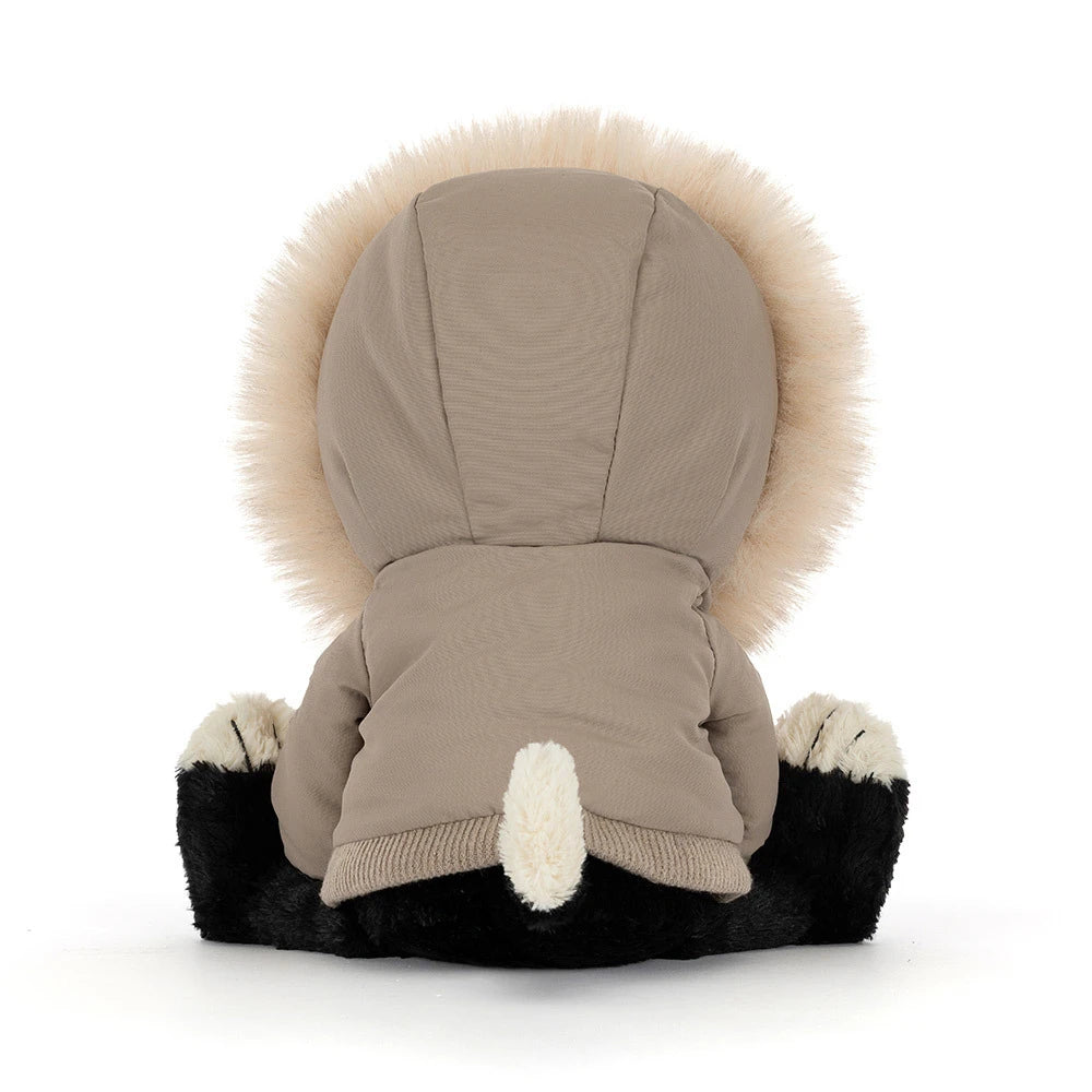 The back of a plush dog toy wearing a beige parka with a large cream faux-fur hood and black-and-white paws and face, photographed on a clean white background.
