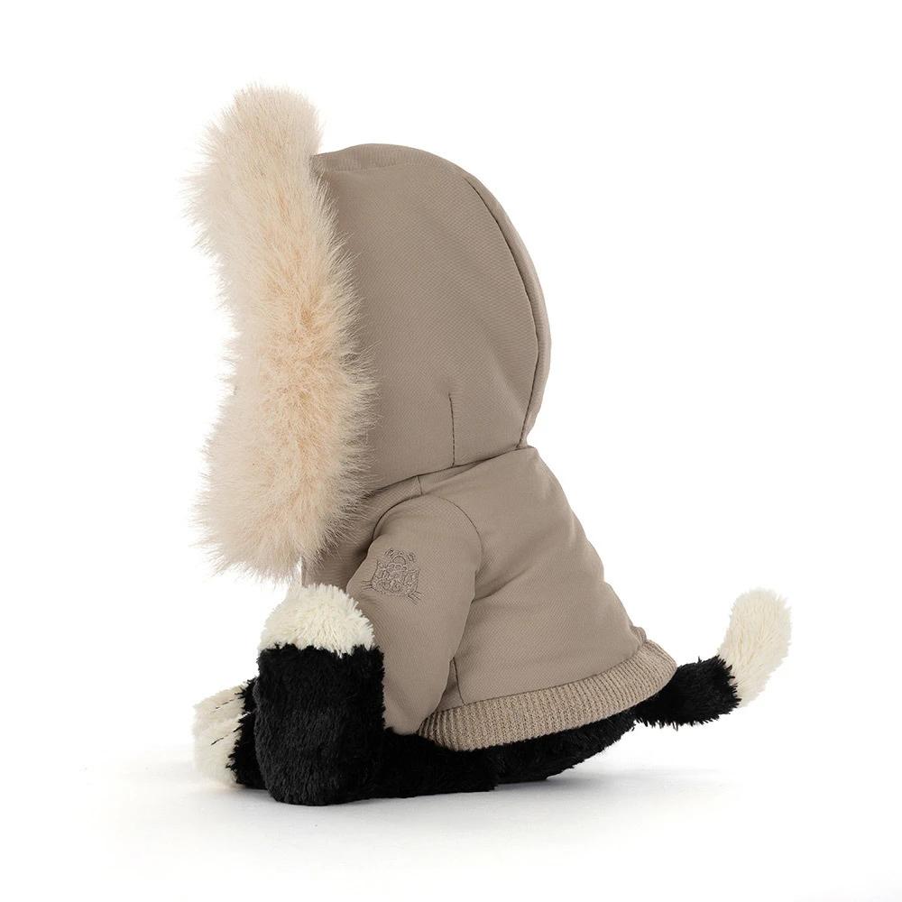 A side of a plush dog toy wearing a beige parka with a large cream faux-fur hood and black-and-white paws and face, photographed on a clean white background.