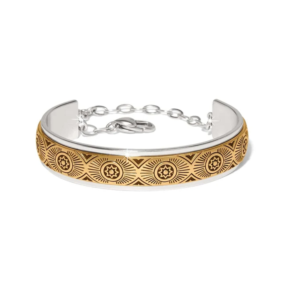 A two-tone silver and gold cuff bracelet with an engraved geometric sunburst pattern on the gold section, shown on a plain white background.