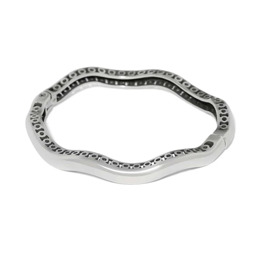 A polished silver-toned metal bangle bracelet with a wavy, scalloped edge and a textured, perforated inner channel, shown on a plain white background.