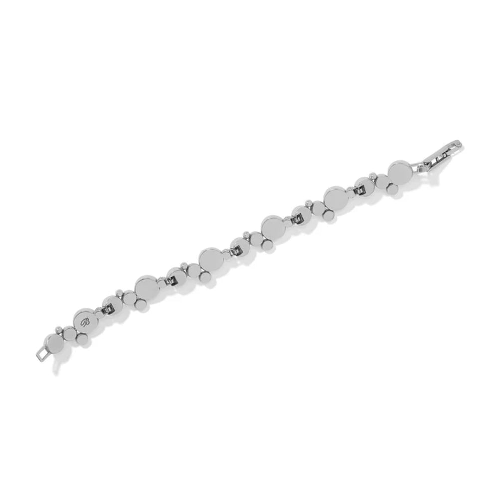 The underside of a silver bracelet with different size round silver pieces connected by small hinges on a white background.