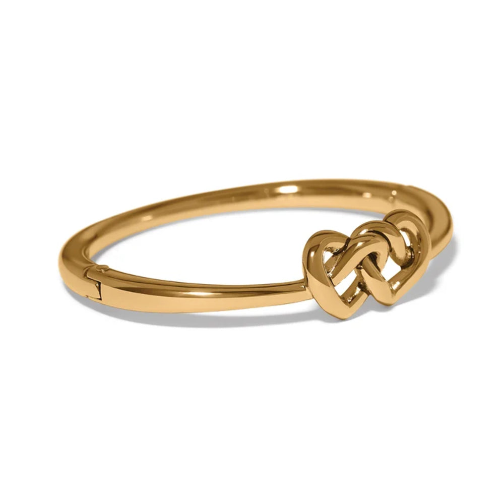 A polished yellow gold hinged bangle bracelet with a central interlocking heart design, shown on a clean white background.