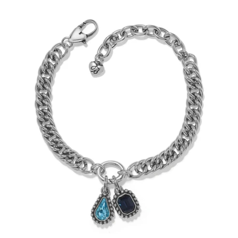 A silver-tone Cuban link chain bracelet with two dangling charms: a teardrop-shaped light blue gemstone charm and a rectangular dark blue gemstone charm, shown on a plain white background.