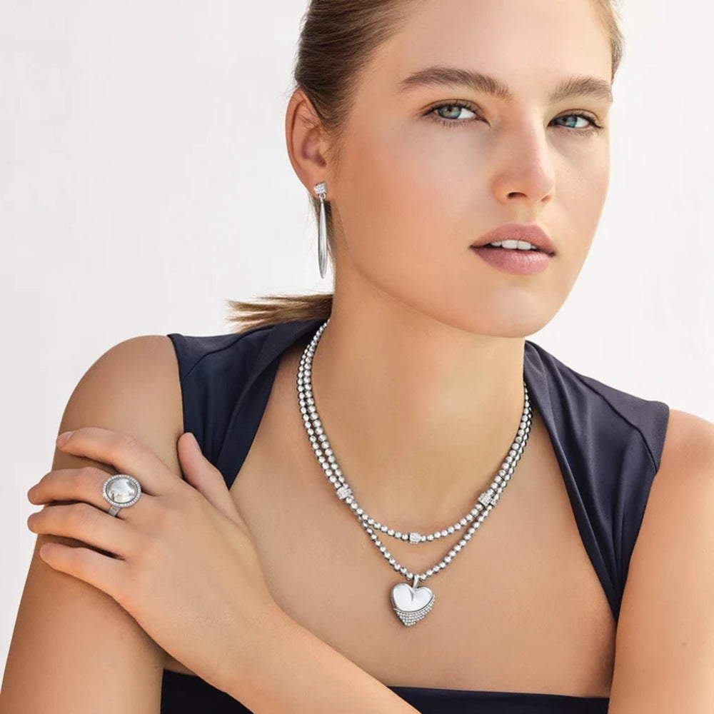 Woman wearing a beaded necklace, earrings, and ring on a plain background
