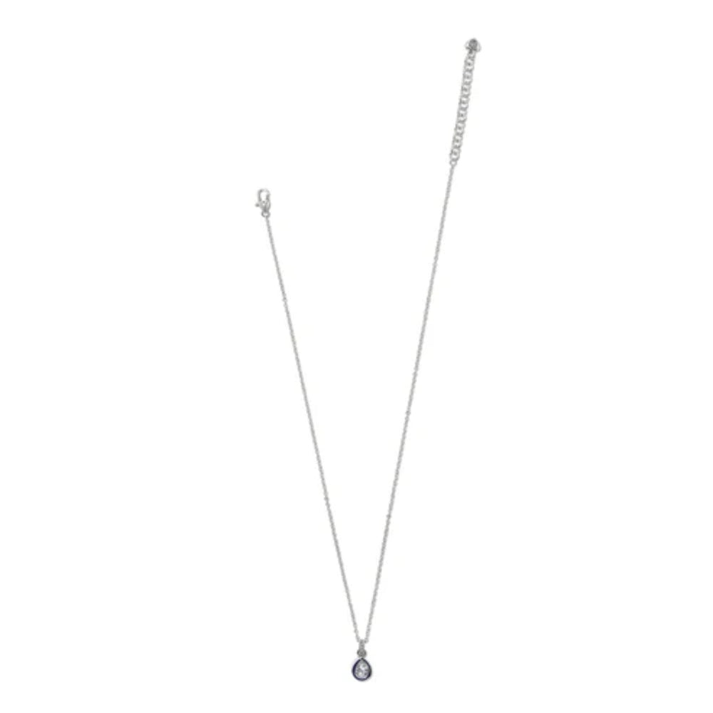 A delicate silver chain necklace with a small teardrop-shaped dark blue gemstone pendant, displayed against a solid white background.