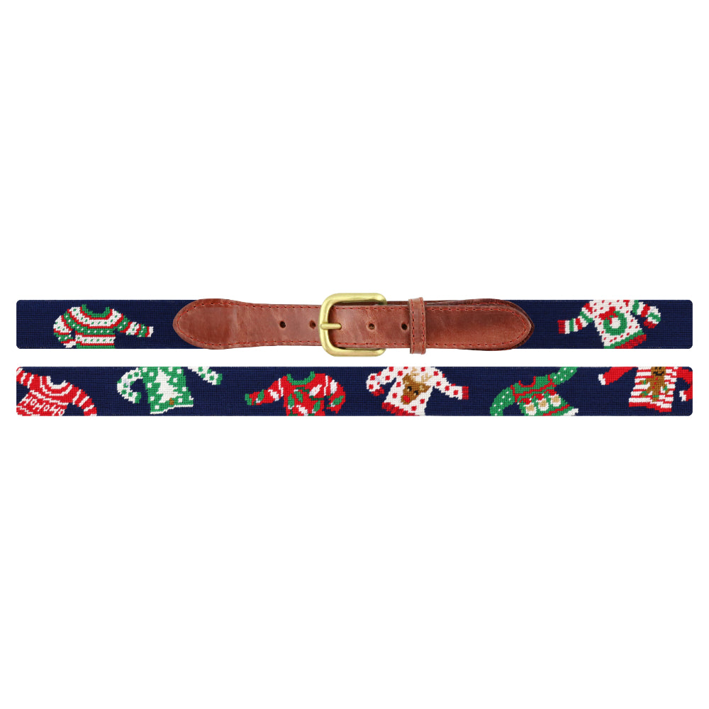 A navy blue woven belt with a brown leather buckle and keeper, decorated with a festive pattern of Christmas sweaters, candy canes, and snowman figures in red, green, and white.