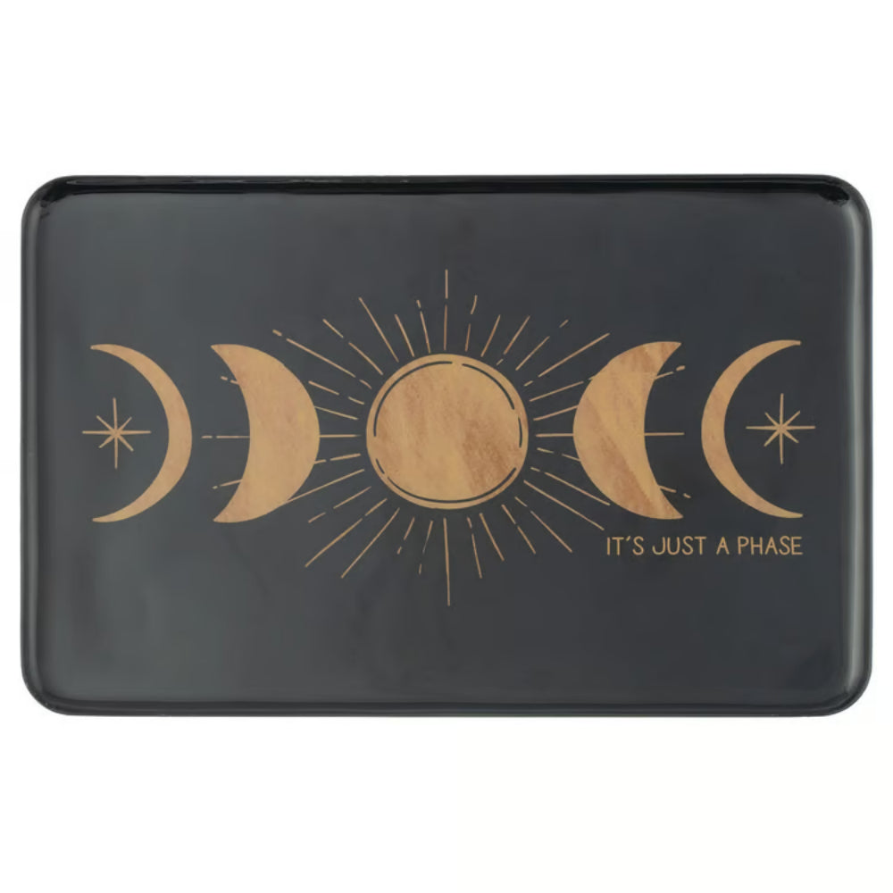 A black rectangular tray with rounded corners featuring a gold celestial design of moon phases and a sun with the text 'IT'S JUST A PHASE' printed on the front.
