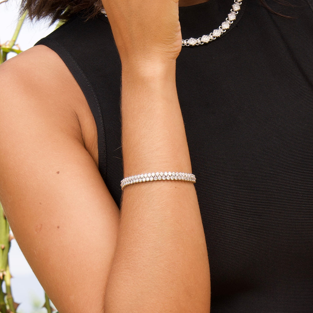 Close-up of a person wearing a double row diamond bracelet on a blurred natural background