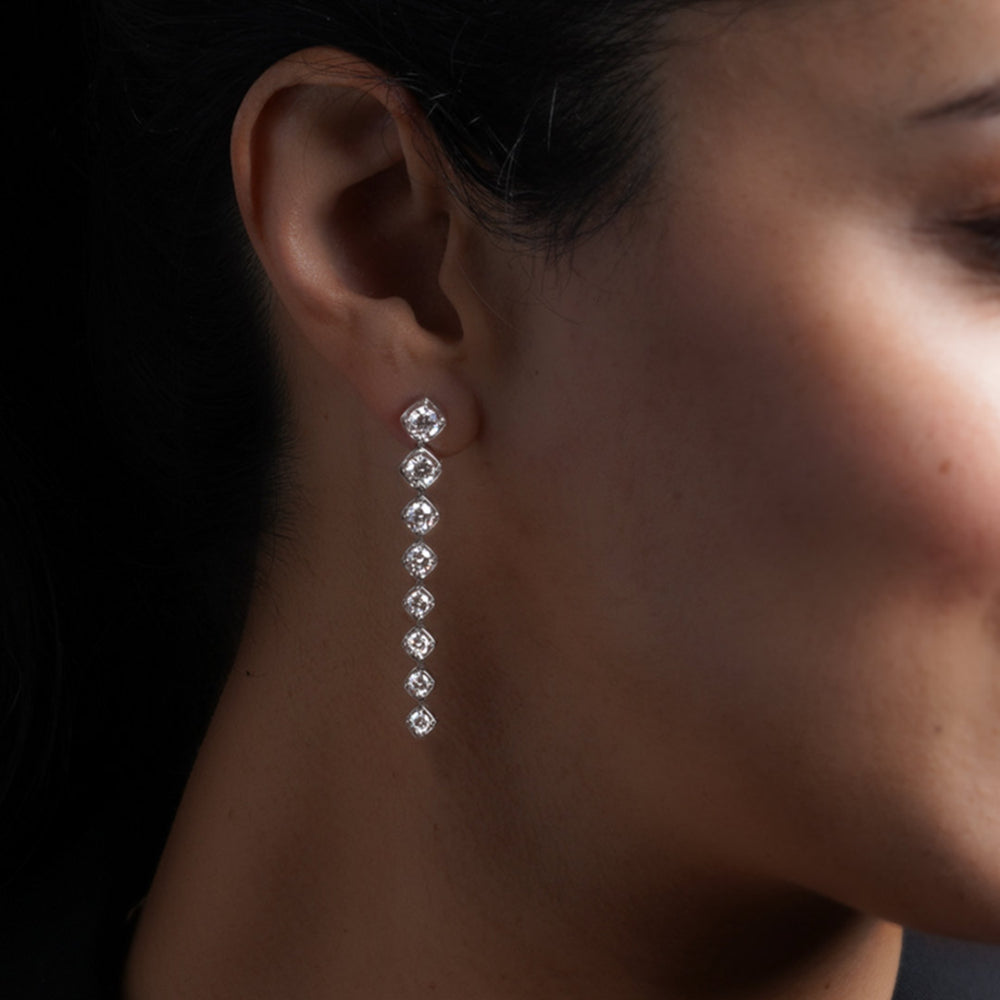 Close-up of a woman wearing a diamond drop earring with a dark background