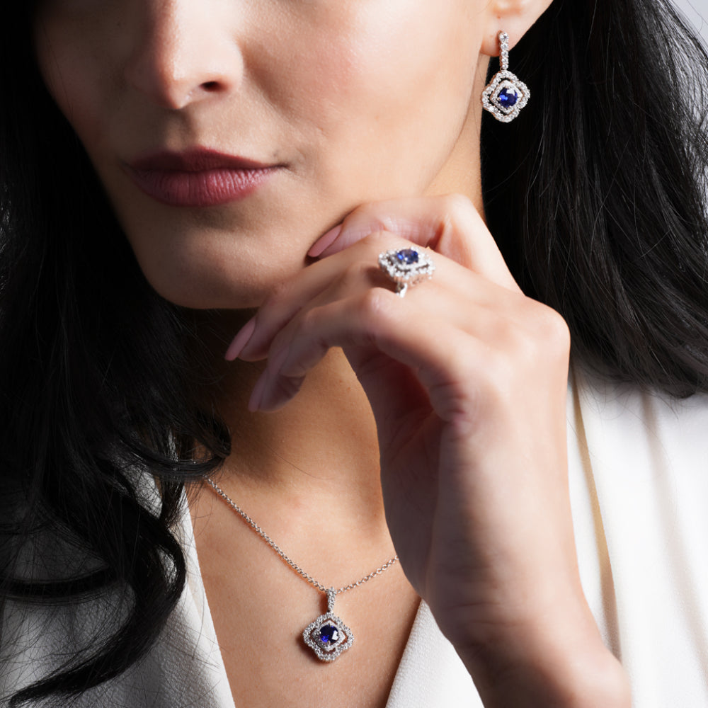 Close-up of a woman wearing a sapphire and diamond ring, necklace, and earrings