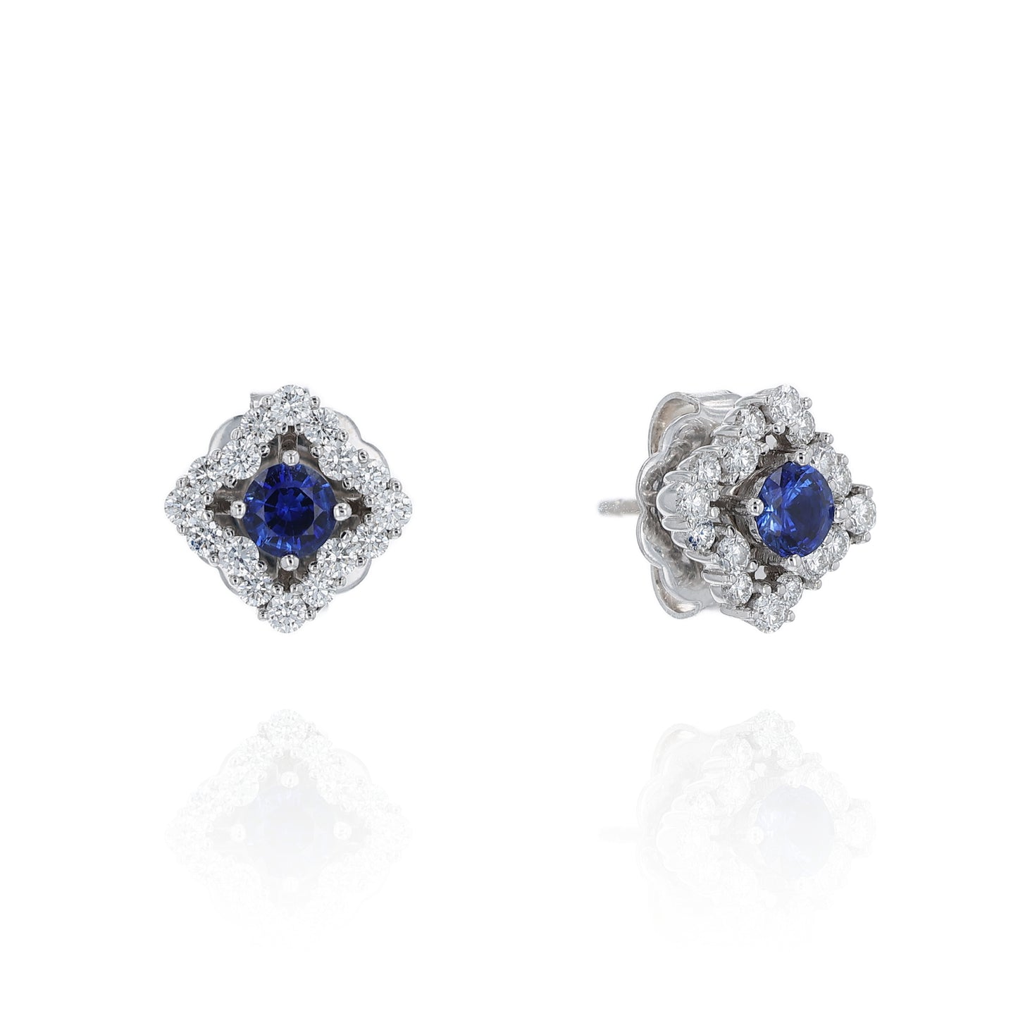 Pair of earrings with round blue sapphire centers and surrounding diamond halos on a white background