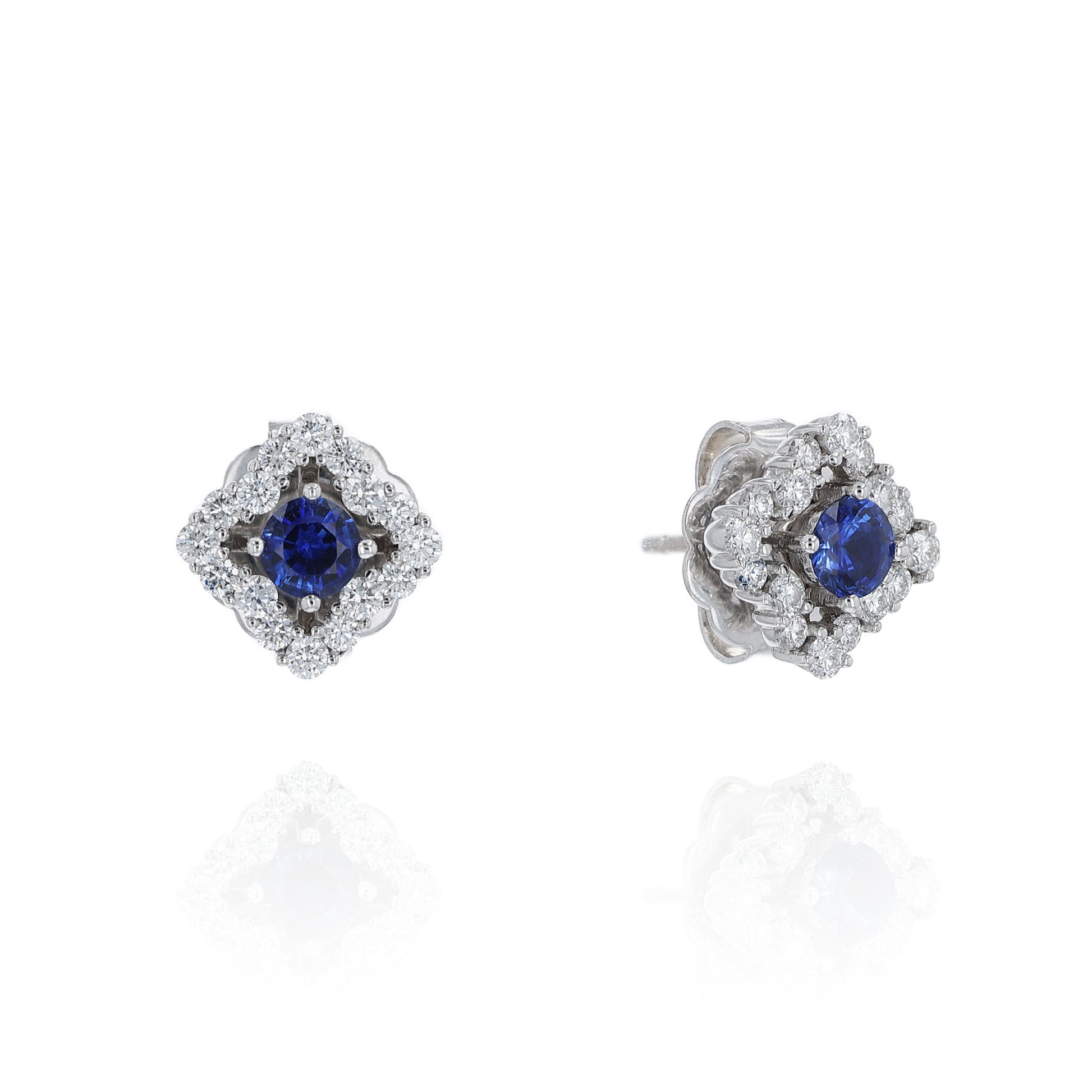 Pair of earrings with round blue sapphire centers and surrounding diamond halos on a white background