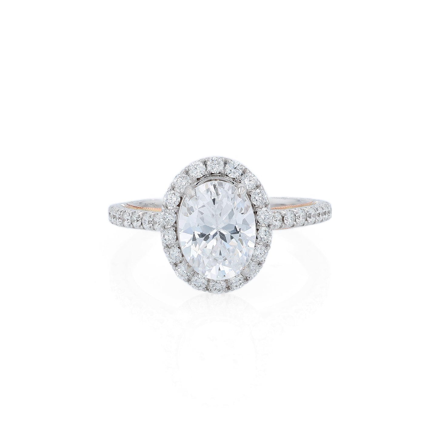 White and rose gold and diamond halo engagement ring with diamond accents and an oval cubic zirconia center on a white background