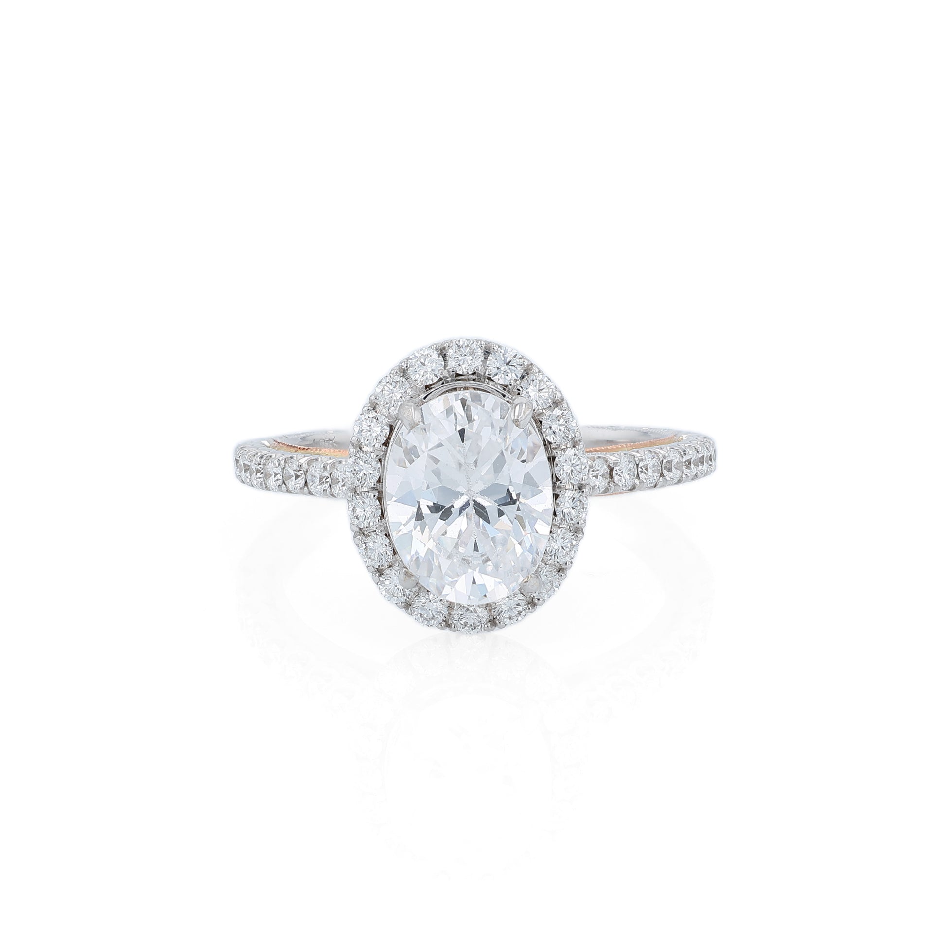 White and rose gold and diamond halo engagement ring with diamond accents and an oval cubic zirconia center on a white background
