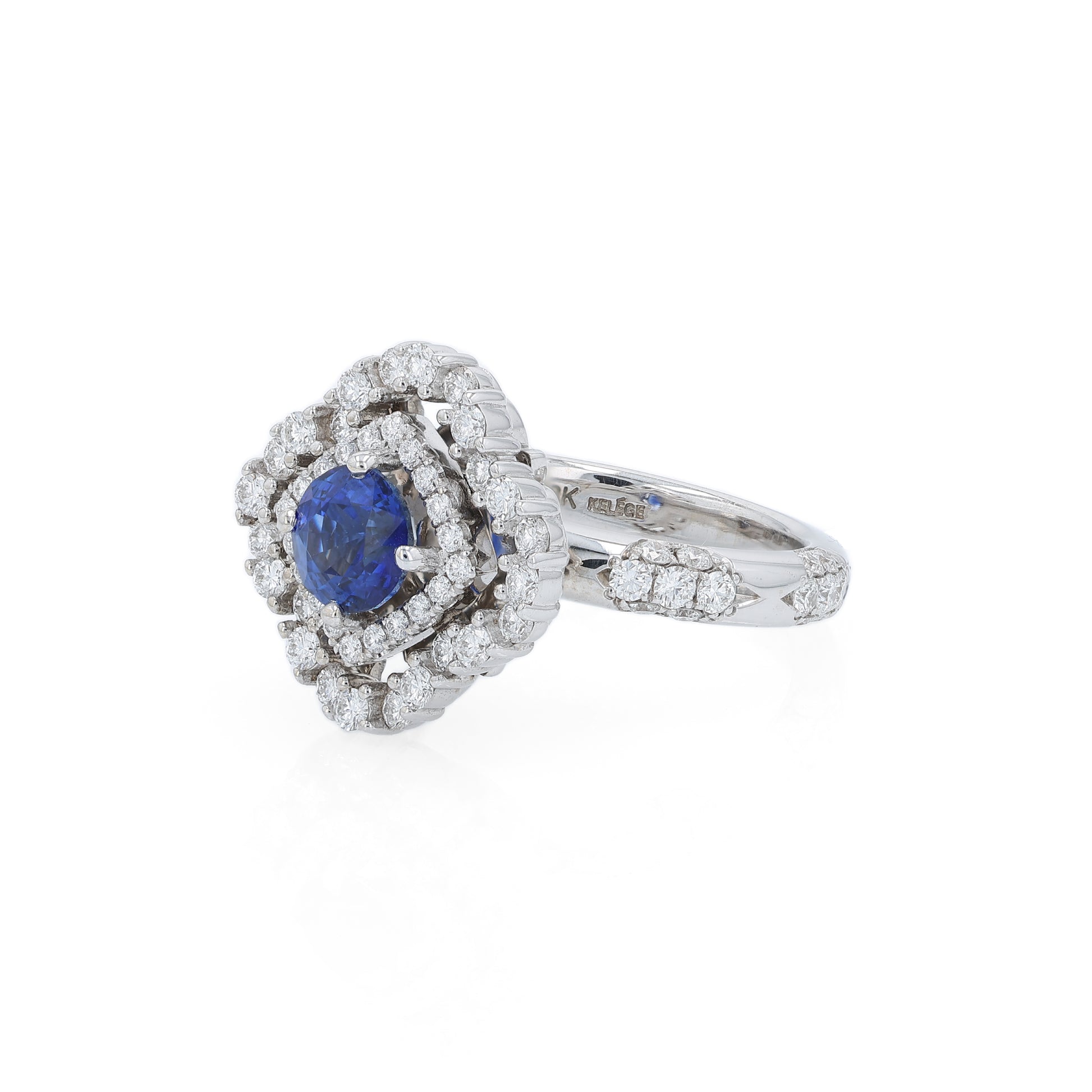 White gold diamond double halo ring with a blue sapphire center stone on a white background