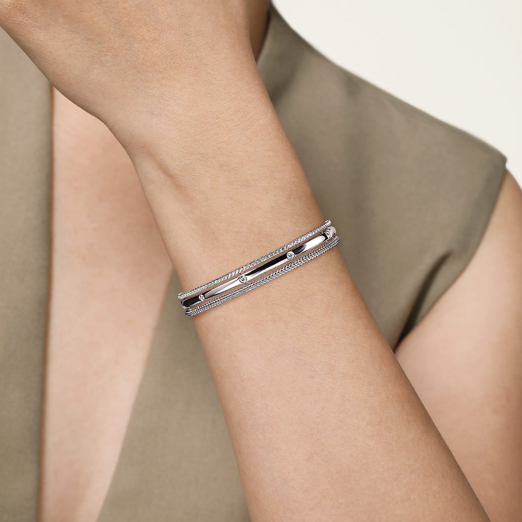 Silver bracelet on a person's wrist with a neutral background