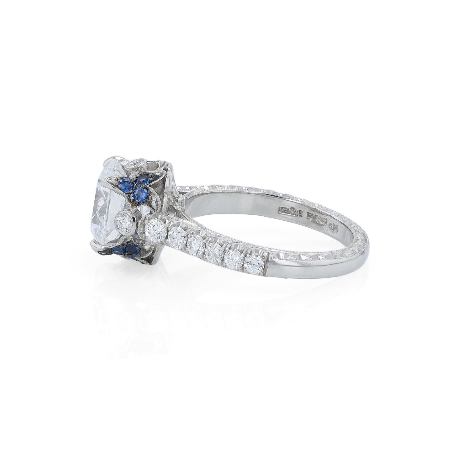 Platinum diamond engagement ring with diamond and sapphire accents and a round cubic zirconia center on a white background