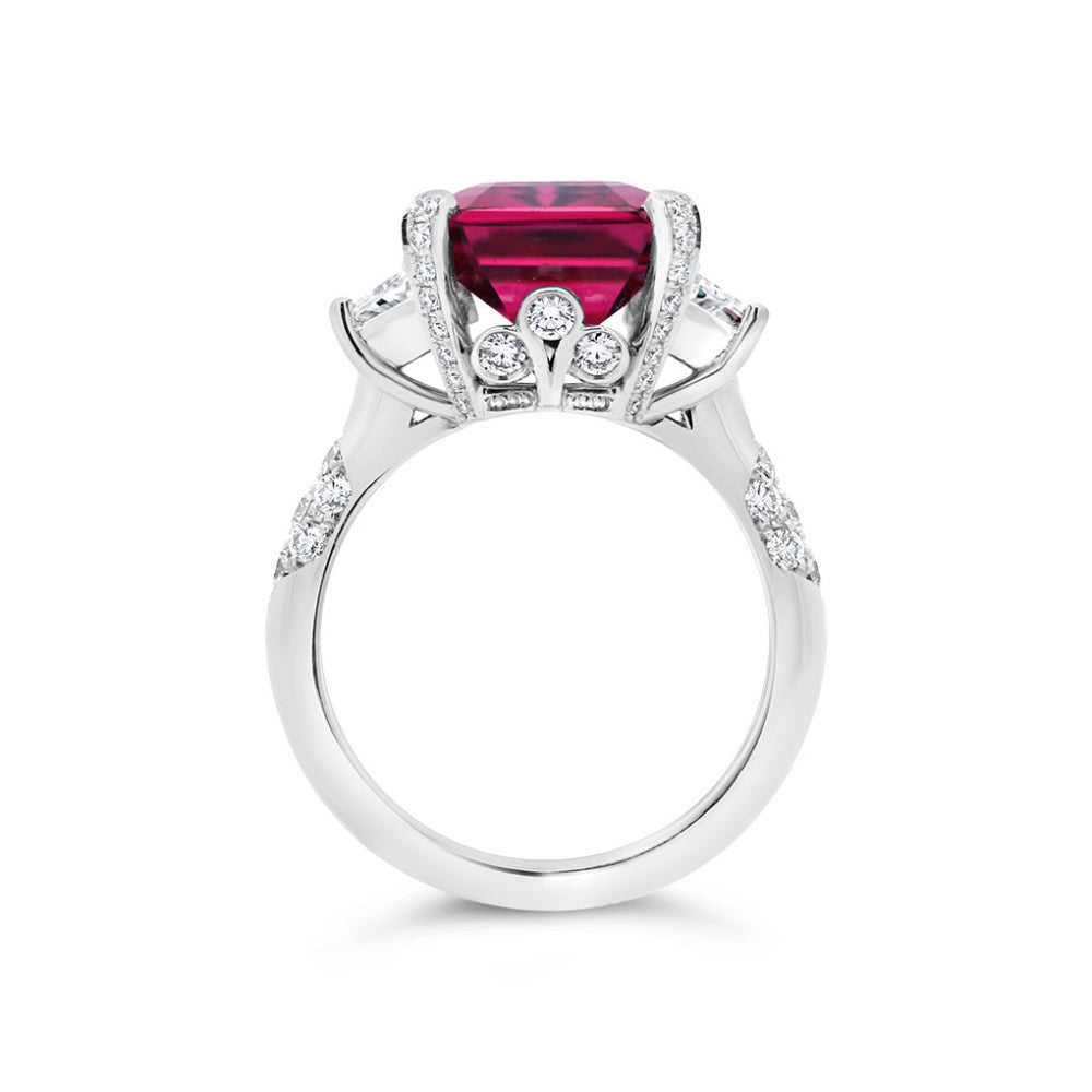 Platinum ring with a rubellite center and diamond accents on a white background