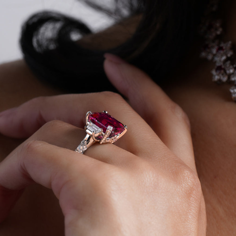 Close-up of a hand wearing a ring with a pink gemstone and platinum band