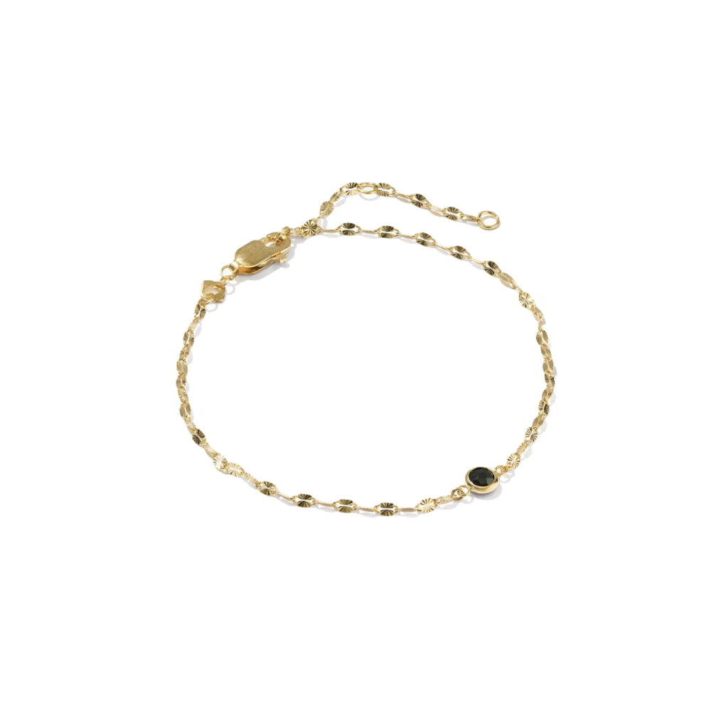 A delicate gold chain bracelet with a small round black stone accent, displayed on a clean white background.