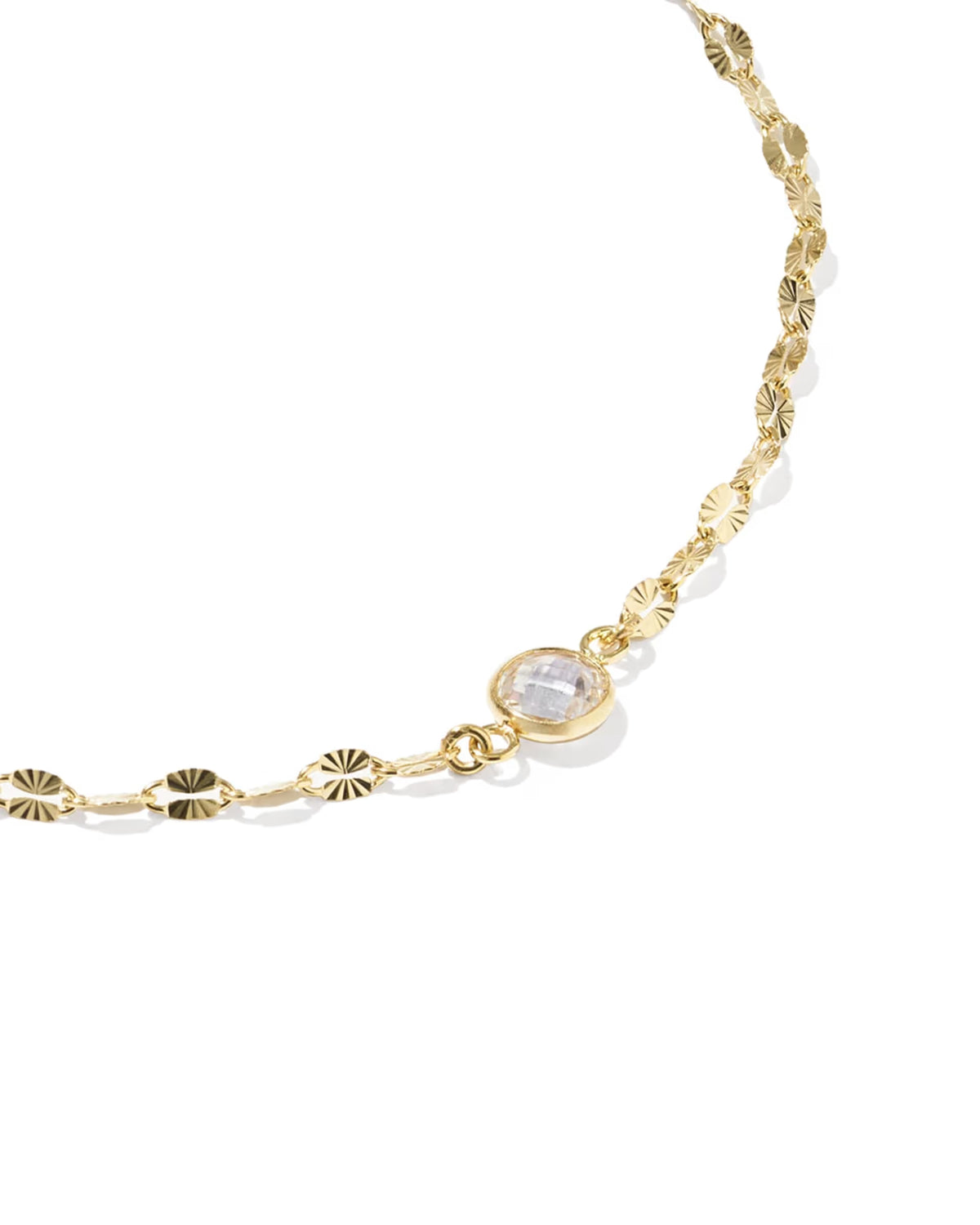 A gold chain bracelet featuring textured sunburst links and a central oval bezel-set clear gemstone, shown on a clean white background.