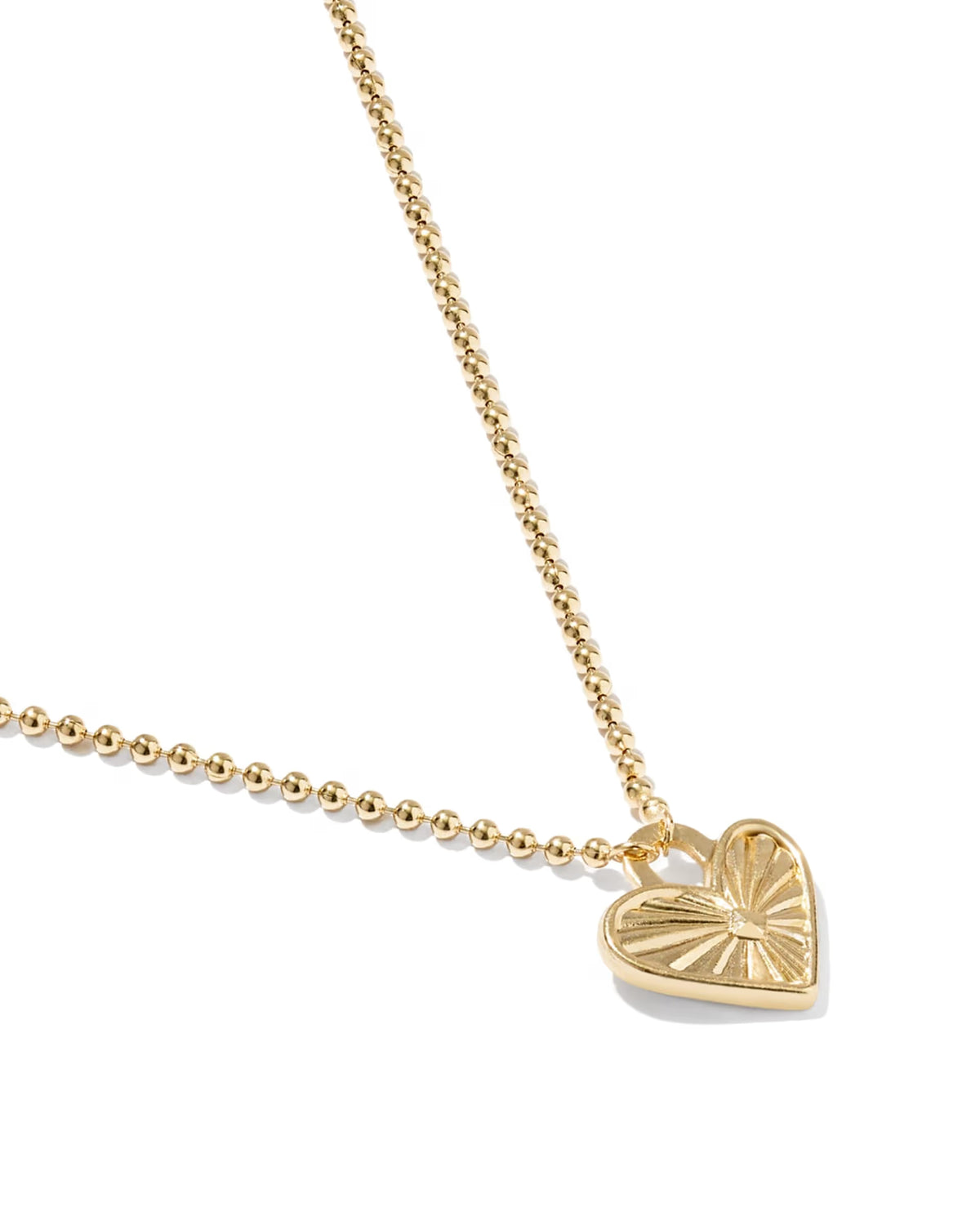 A gold heart pendant necklace with a textured, sunburst-like pattern on a delicate gold ball chain, shown on a clean white background.