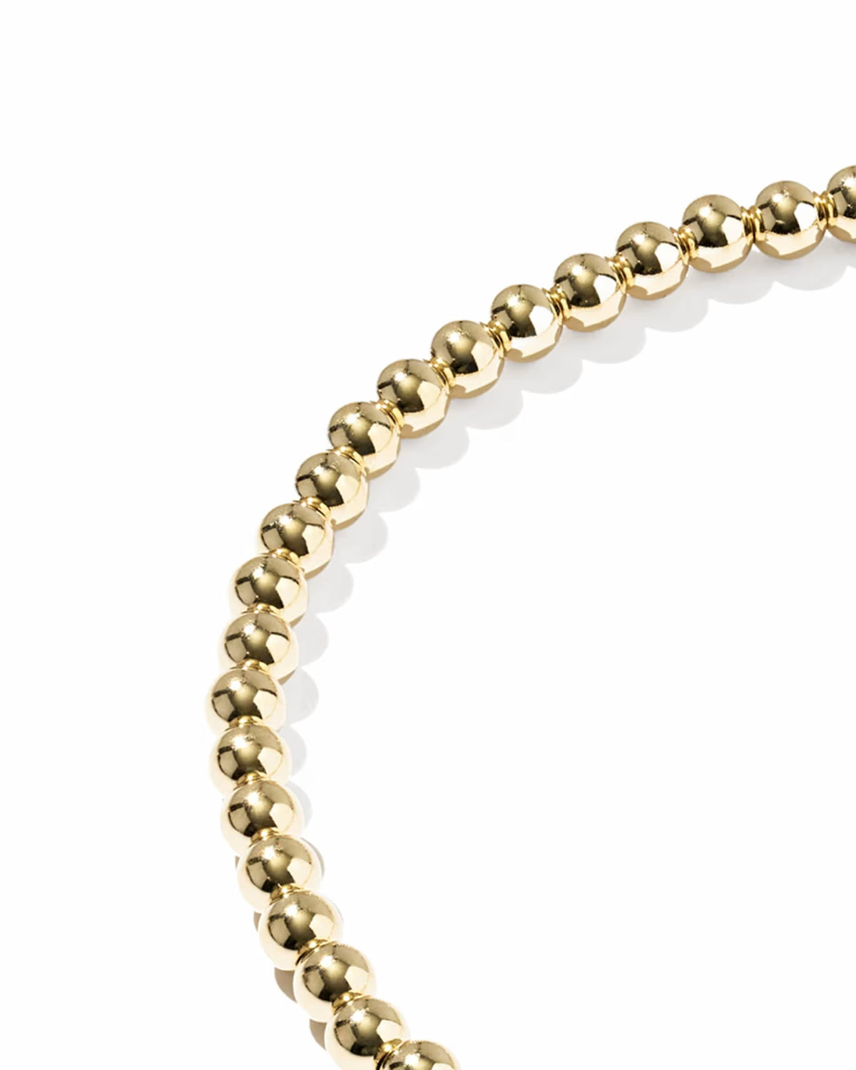 A close-up of a gold beaded stretch bracelet shown against a plain white background.