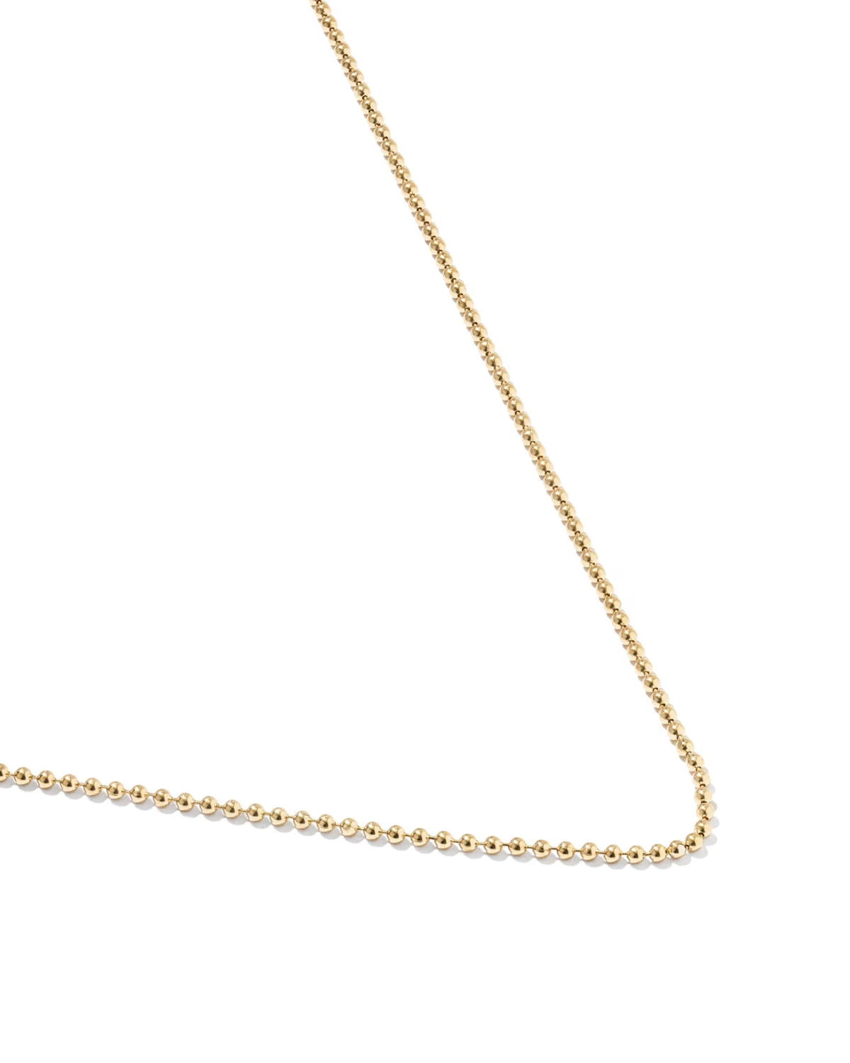 A delicate gold beaded chain necklace shown on a plain white background, with the chain extending diagonally and horizontally across the lower portion of the frame.