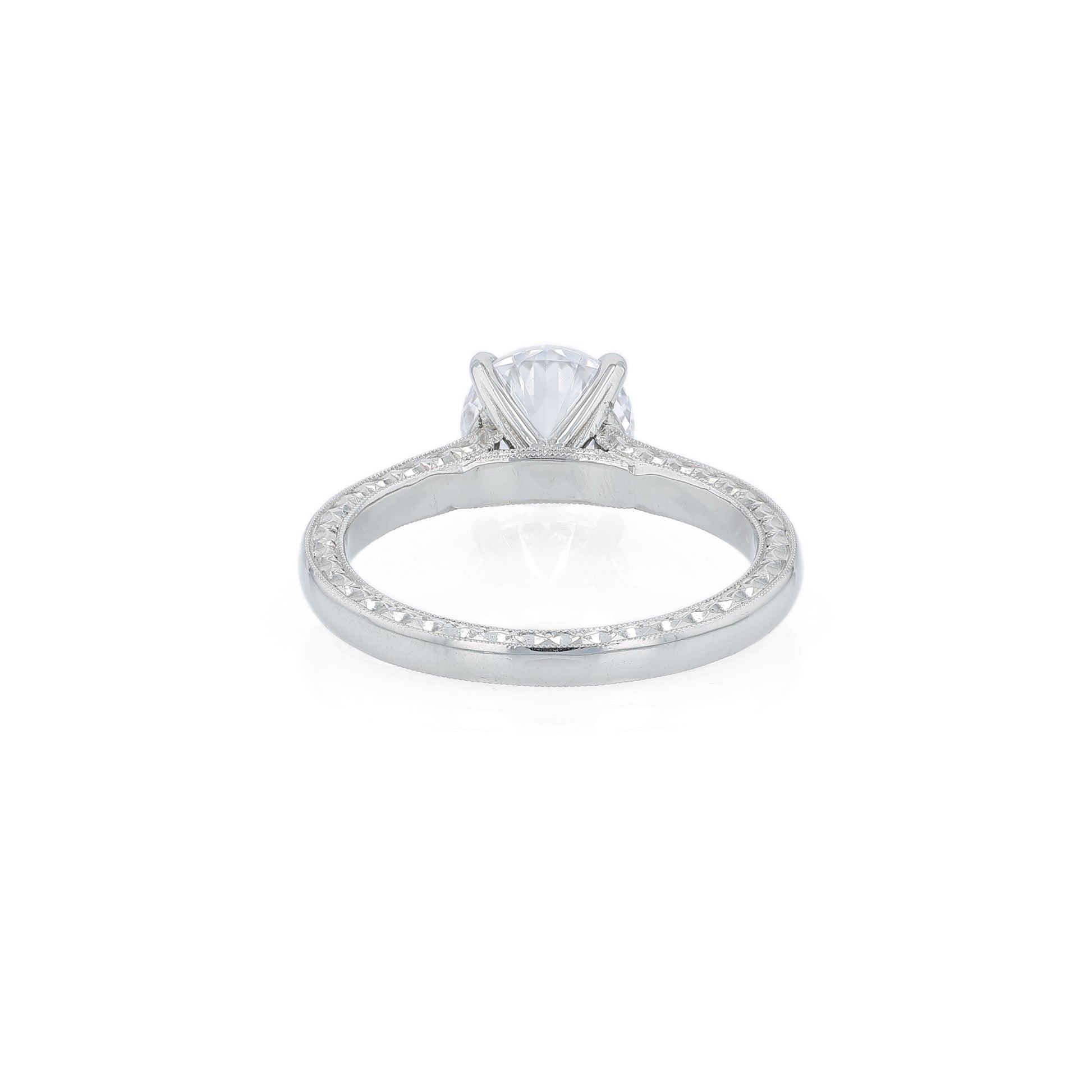 Platinum diamond solitaire engagement ring with engraved sides and a round cubic zirconia center on a white background