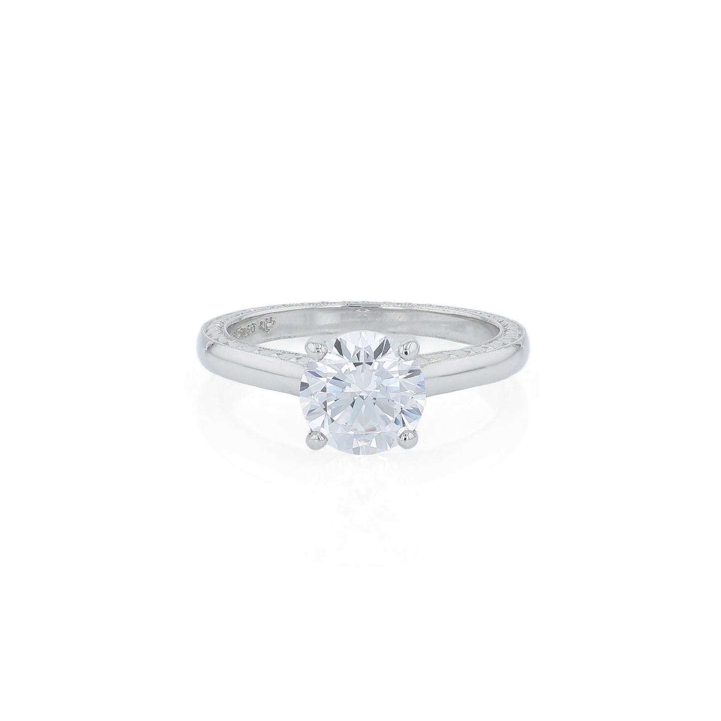 Platinum diamond solitaire engagement ring with engraved sides and a round cubic zirconia center on a white background
