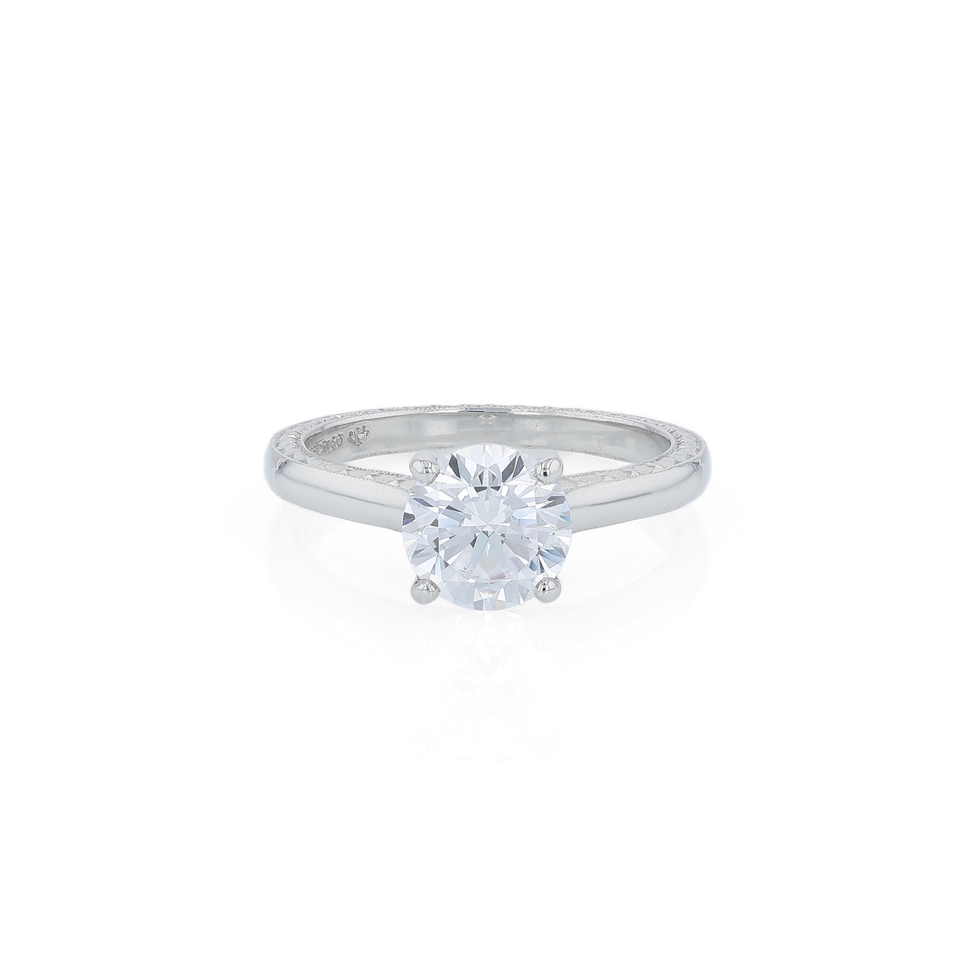 Platinum diamond solitaire engagement ring with engraved sides and a round cubic zirconia center on a white background