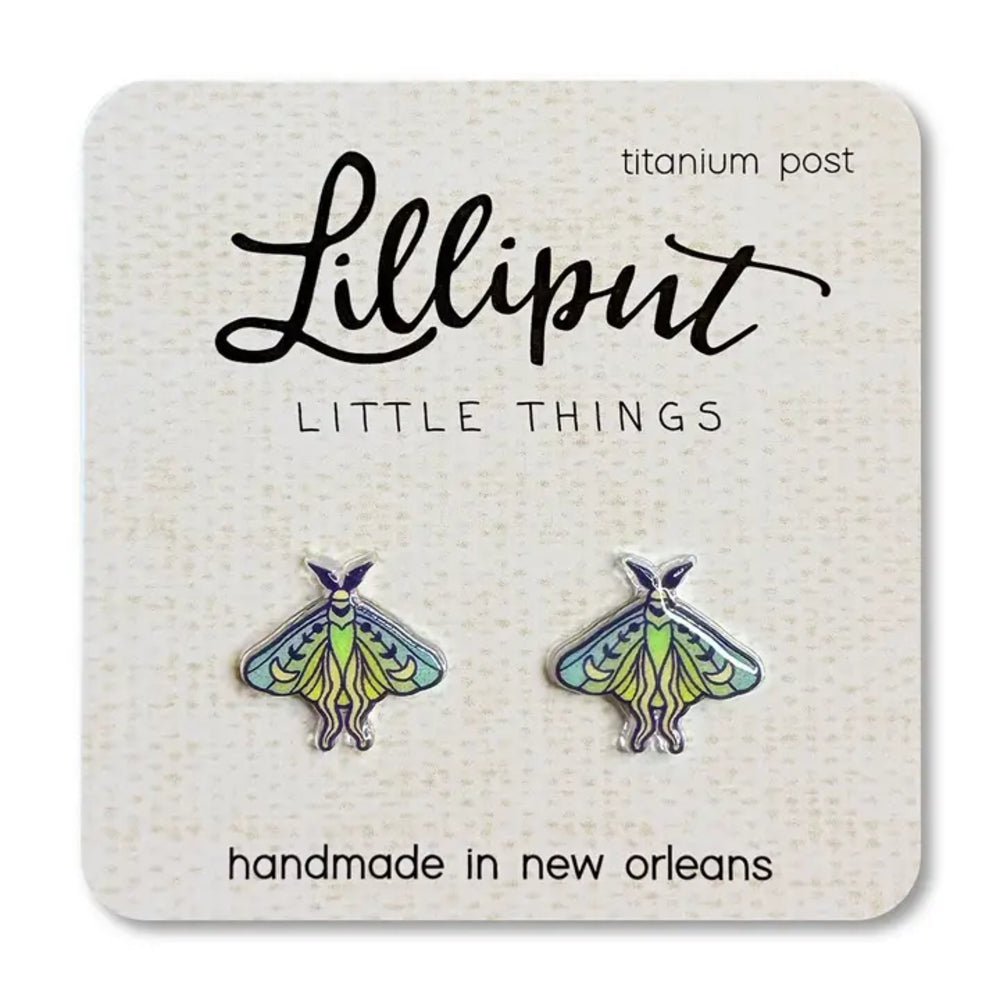 A pair of Lilliput Little Things enamel moth earrings on a white textured display card. The moths have green and yellow bodies with blue and purple wings, set in silver-tone titanium posts.