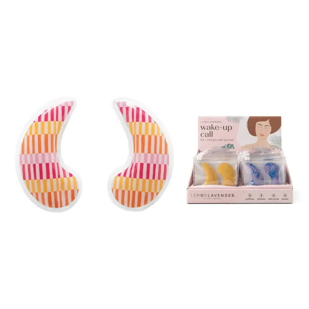Two crescent-shaped eye mask pads with pink, orange, and yellow striped patterns shown next to their retail display box labeled 'wake-up call' by L'Enroëlavender.
