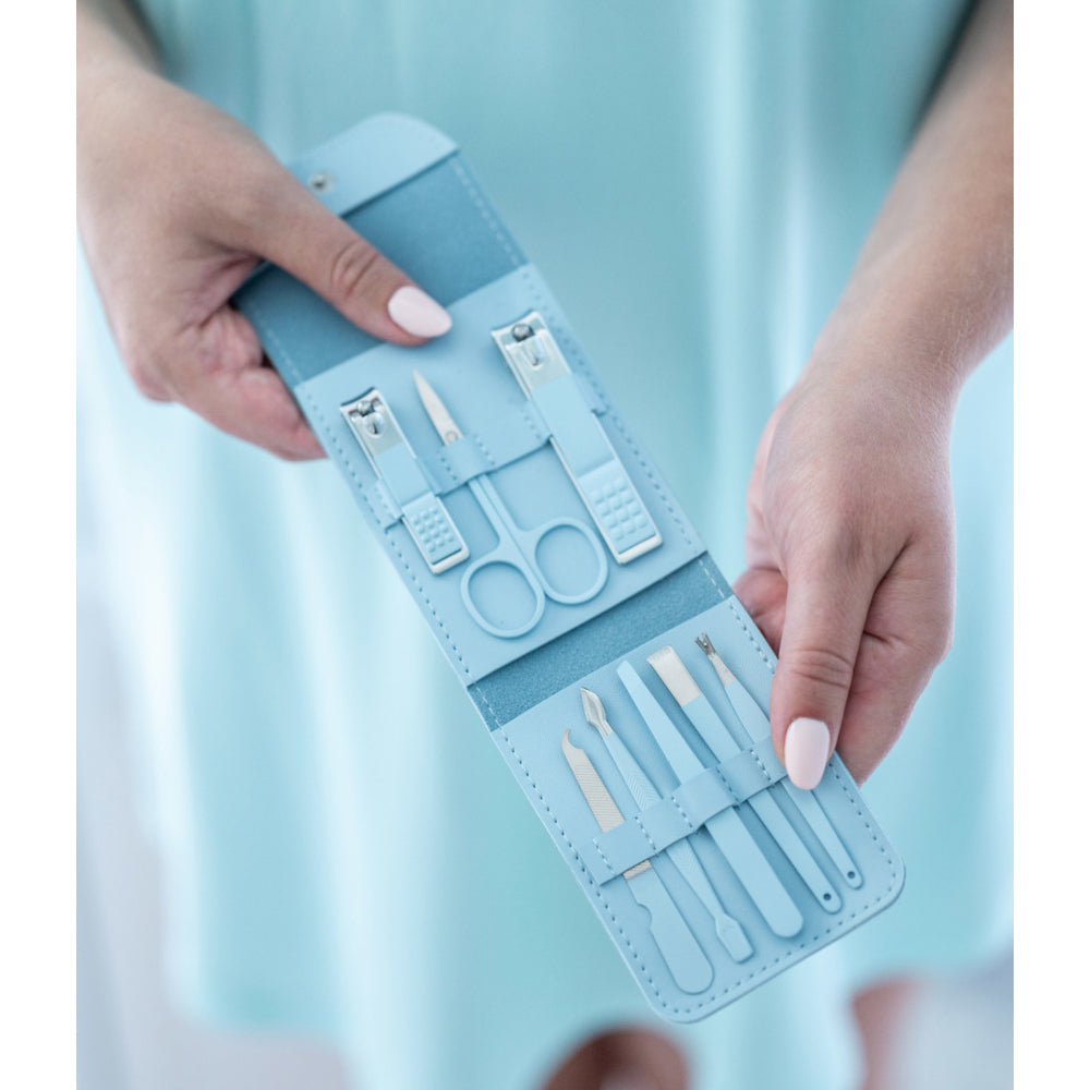 Blue manicure set with tools held by hands against a light blue background