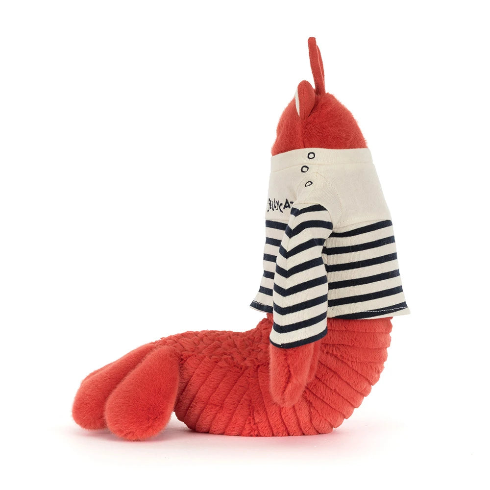 A side photo of stuffed animal red lobster in a sailor outfit with a white & blue striped shirt that says "Jellycat" in the upper left hand corner in blue on a white backround 
