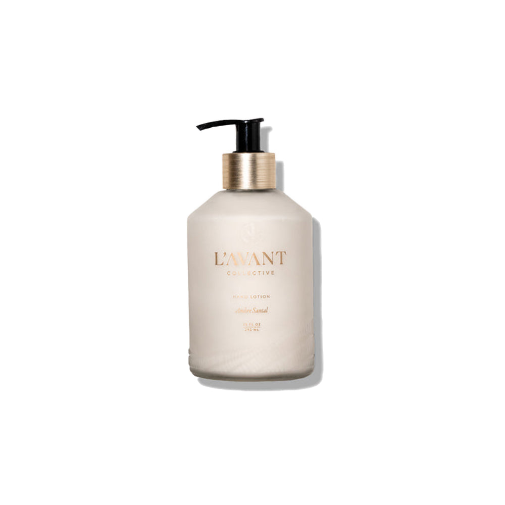 A frosted glass pump bottle of L'Avant Collective Hand Lotion in a warm off-white color, featuring a metallic gold collar and a black pump dispenser, set against a plain white background with a soft shadow.