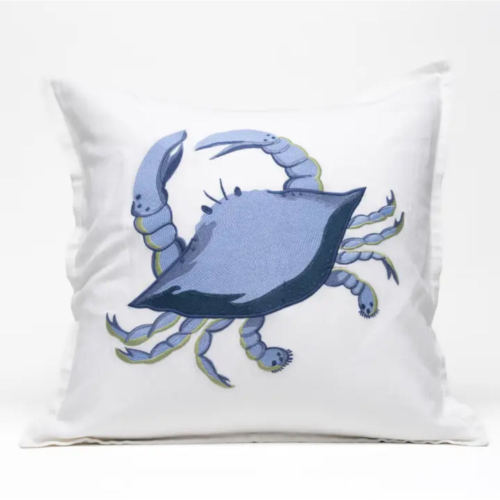 A square white throw pillow featuring a stylized embroidered blue crab in the center, set against a clean white background.