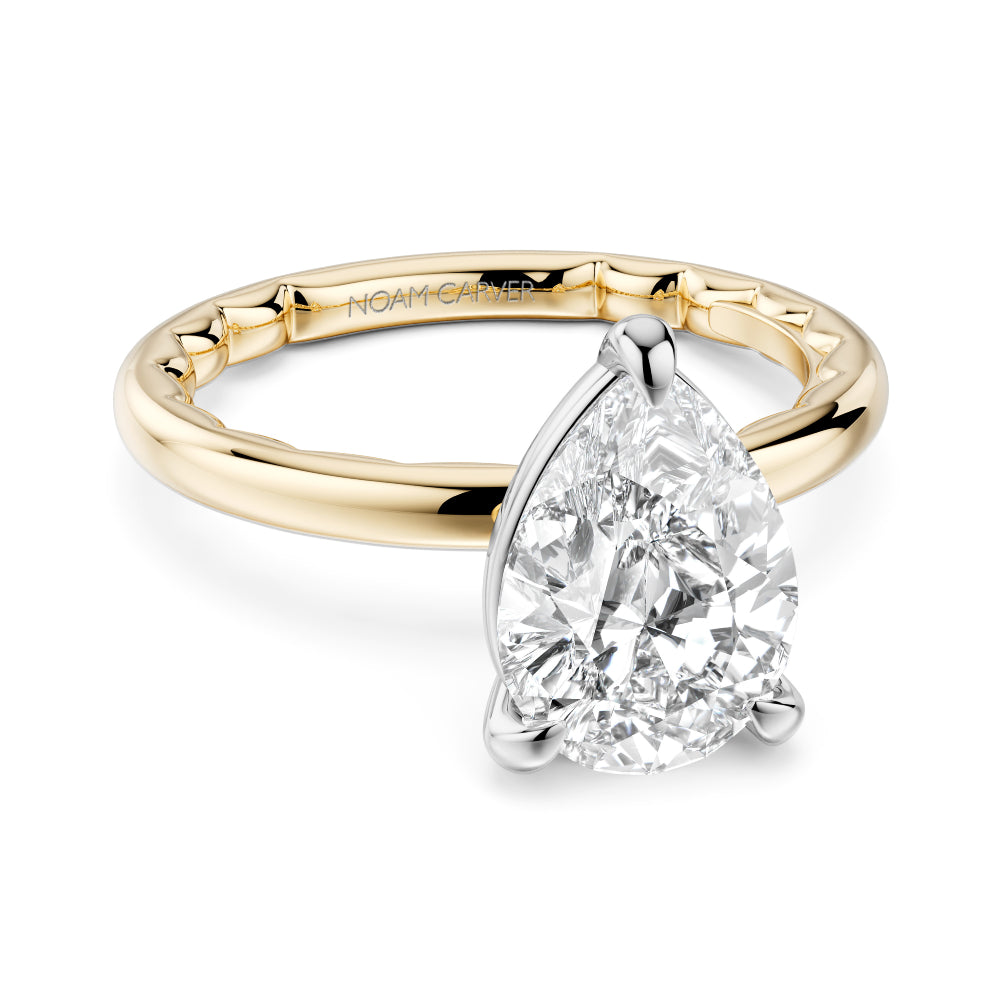 Gold Noam Carver ring with a pear-shaped diamond on a white background