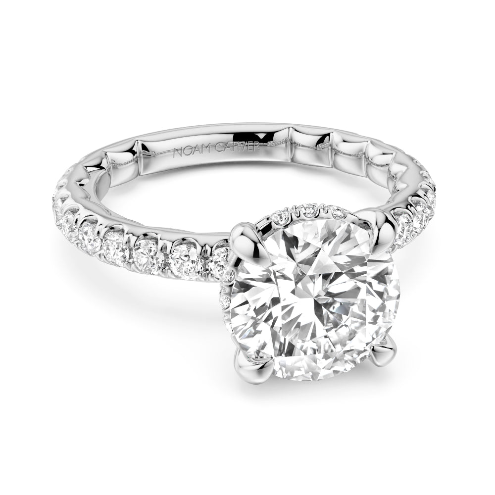 Diamond white gold Noam Carver ring with a round center diamond and side diamonds on a white background