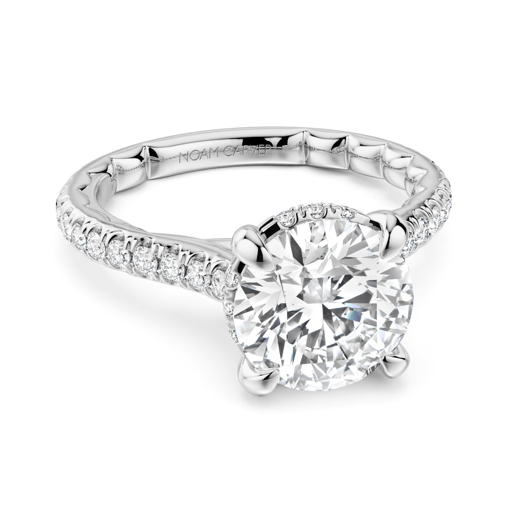 Diamond white gold Noam Carver ring with a round diamond center and diamond sides/hidden halo on a white background