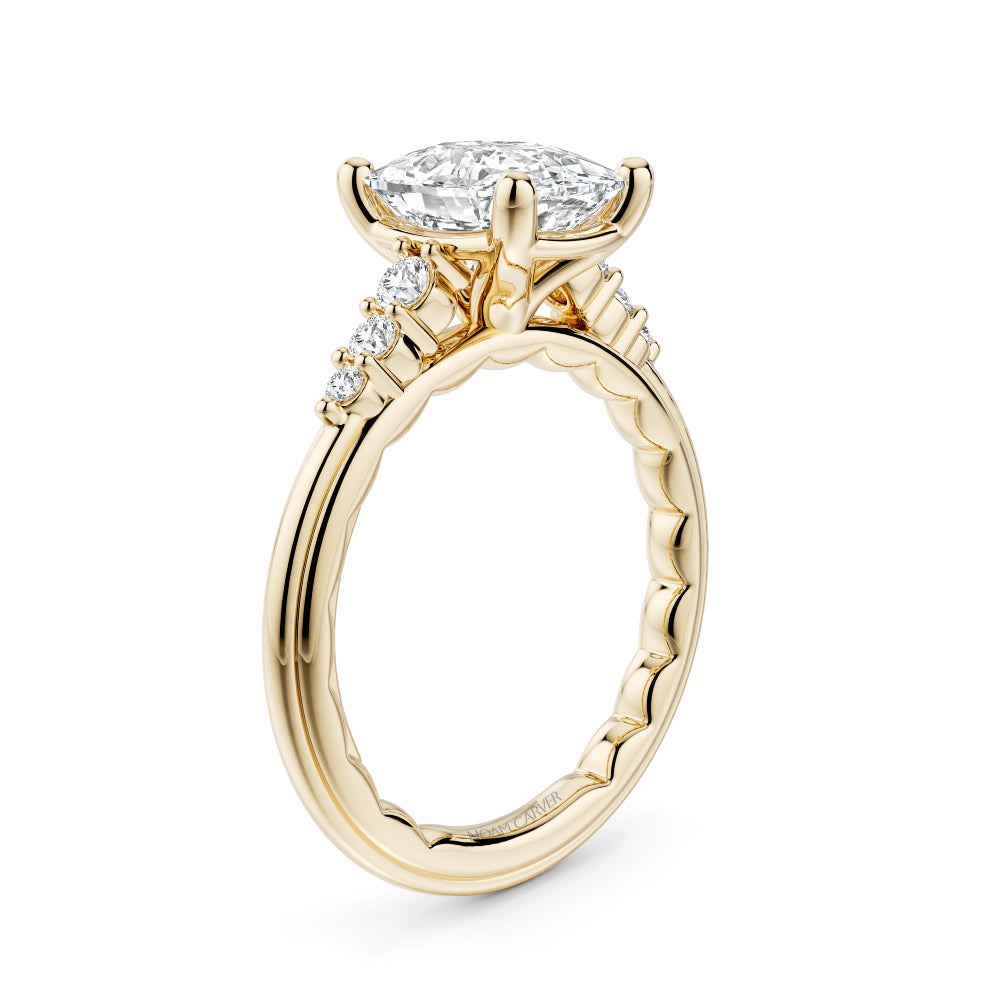 Gold Noam Carver ring with a large elongated cushion diamond and smaller diamonds on the band against a white background